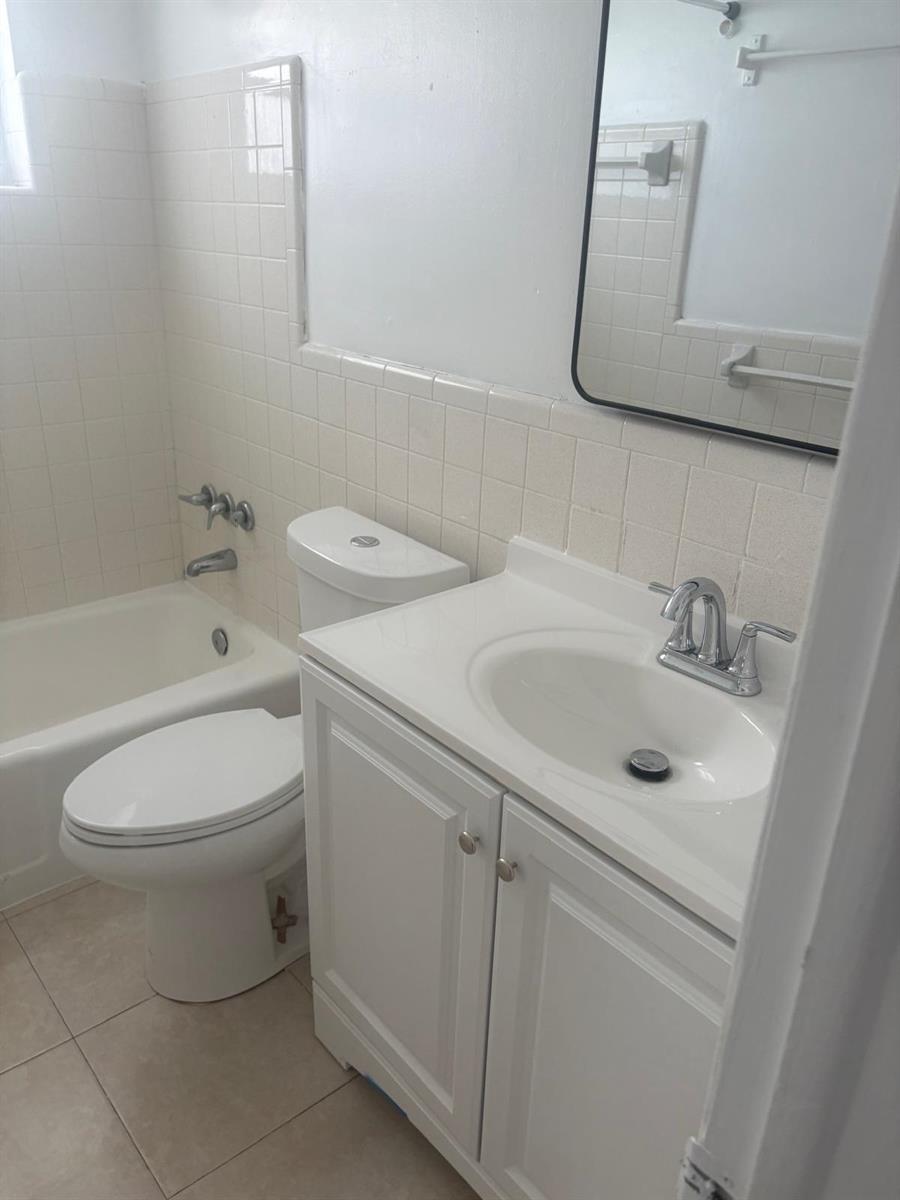 A bathroom features a white vanity, a toilet, and a tiled bathtub shower combination — FORT LAUDERDALE, FL