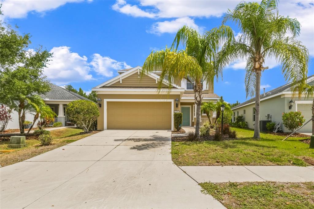 A tan single-story house with a two-car garage, palm tree, and concrete driveway — 12224 LONGVIEW LAKE CIRCLE, BRADENTON, FL