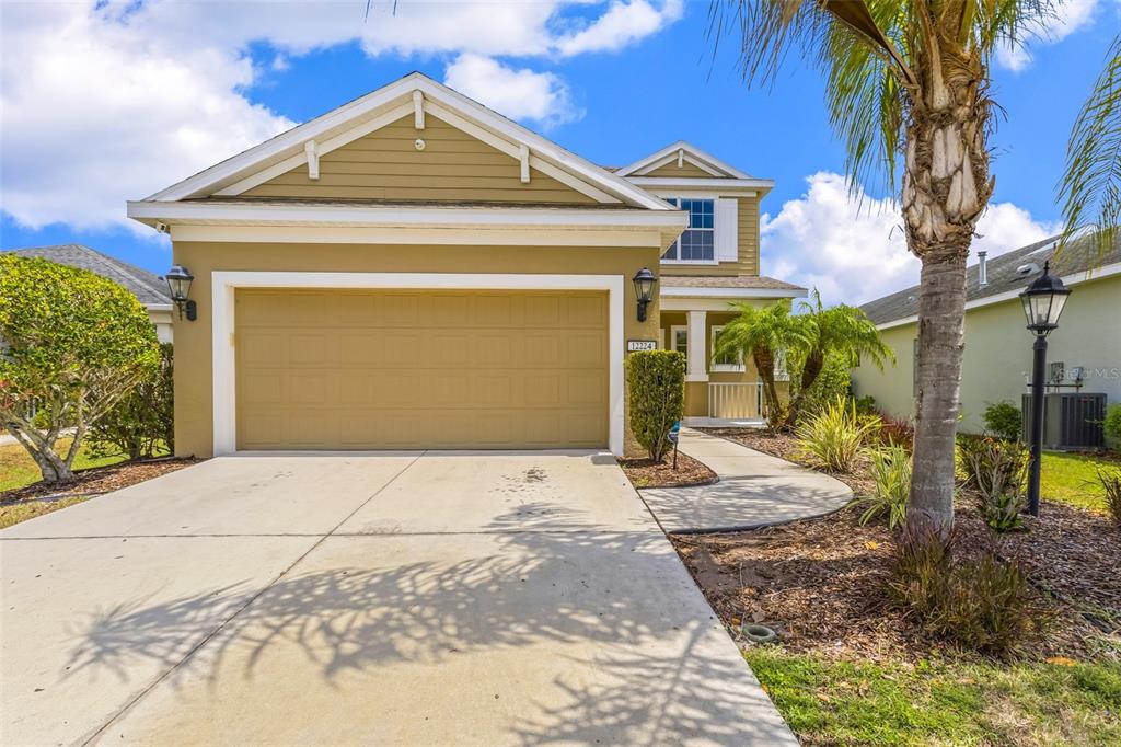 A two-story house with a tan exterior, a two-car garage, and a concrete driveway — 12224 LONGVIEW LAKE CIRCLE, BRADENTON, FL