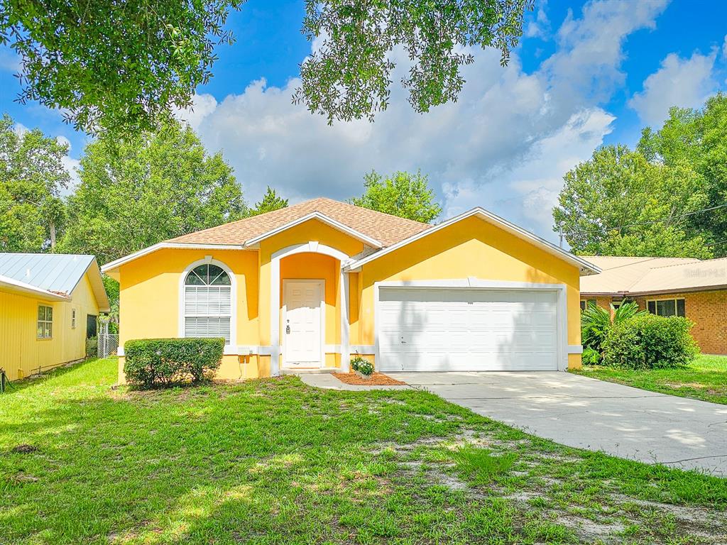 A yellow single-story house with a white garage door and a concrete driveway — 4306 SE 1ST AVENUE, KEYSTONE HEIGHTS, FL