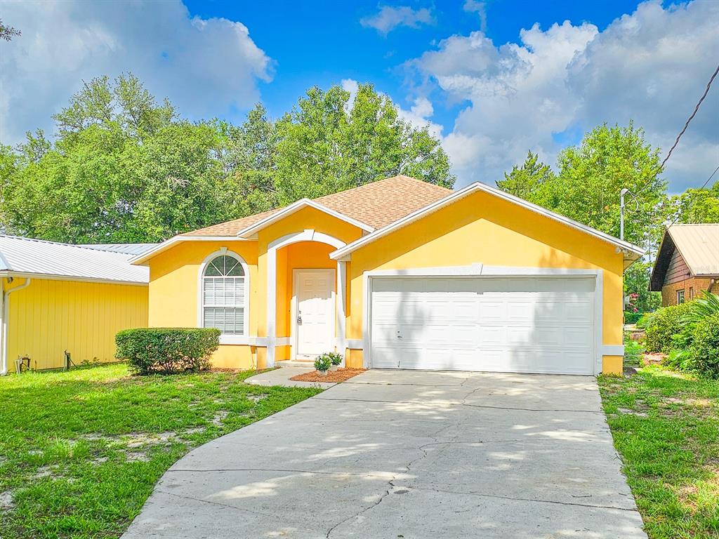 A yellow single-story house with a white garage door and a concrete driveway — 4306 SE 1ST AVENUE, KEYSTONE HEIGHTS, FL