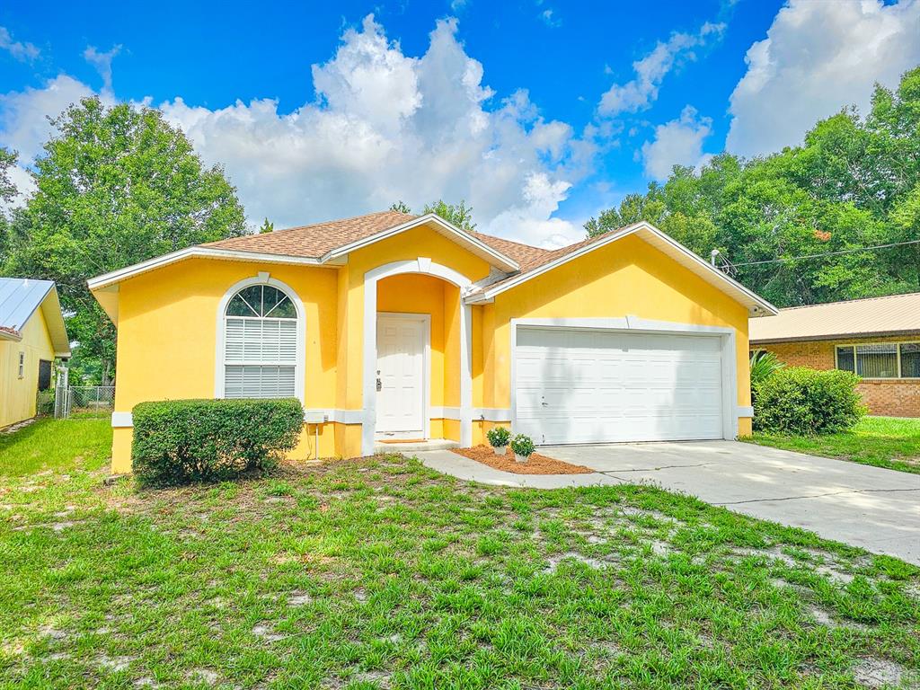 A bright yellow, single-story house with a white garage door and a front entryway — 4306 SE 1ST AVENUE, KEYSTONE HEIGHTS, FL