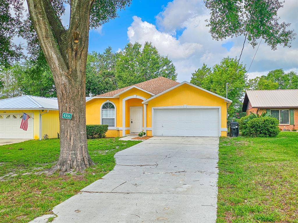 A yellow single-story house with a white garage door and a concrete driveway — 4306 SE 1ST AVENUE, KEYSTONE HEIGHTS, FL