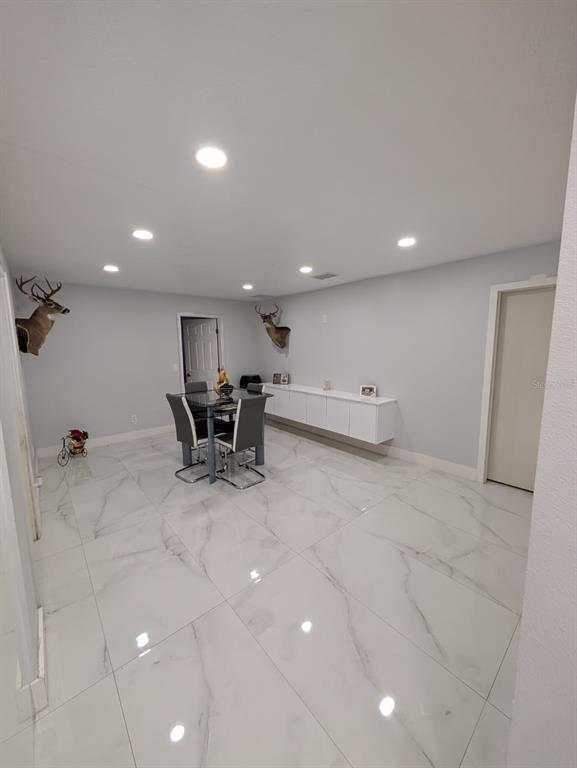A dining room features white marble-look tile flooring, recessed lighting, and two mounted deer heads — 718 PARK MANOR DRIVE, ORLANDO, FL