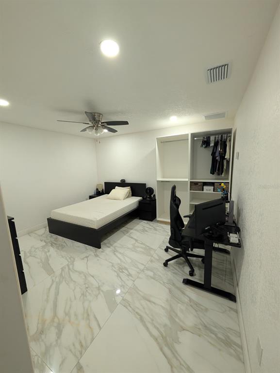 A bedroom features white marble-look tile flooring, a bed, a desk with a chair, and an open closet — 718 PARK MANOR DRIVE, ORLANDO, FL