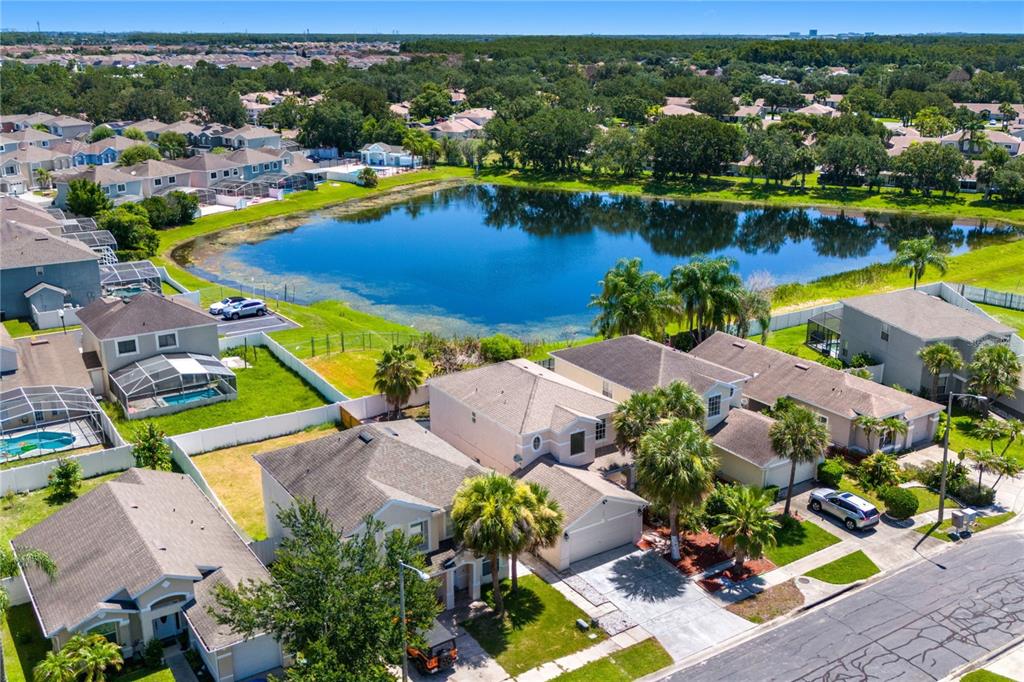 An aerial view shows suburban houses with swimming pools and a pond in the background — 1304 TIMBERBEND CIRCLE, ORLANDO, FL