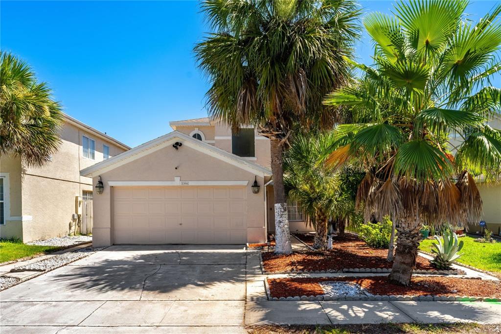 A beige two-story house with a two-car garage and palm trees in the front yard — 1304 TIMBERBEND CIRCLE, ORLANDO, FL
