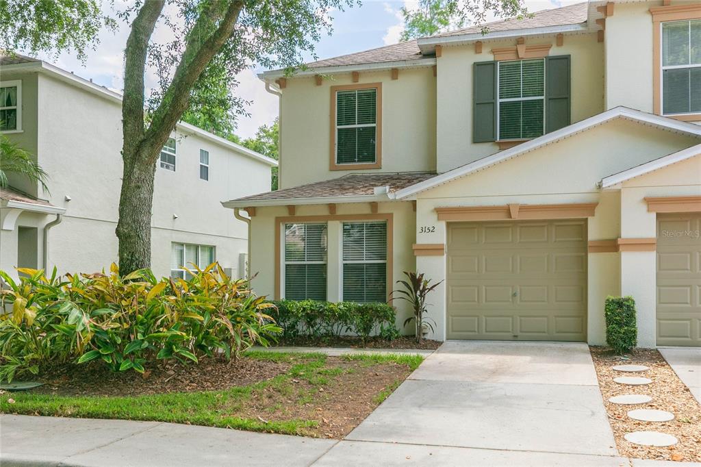 A two-story townhouse with a beige stucco exterior, a single-car garage, and front landscaping — 3152 ROYAL TUSCAN LANE, VALRICO, FL