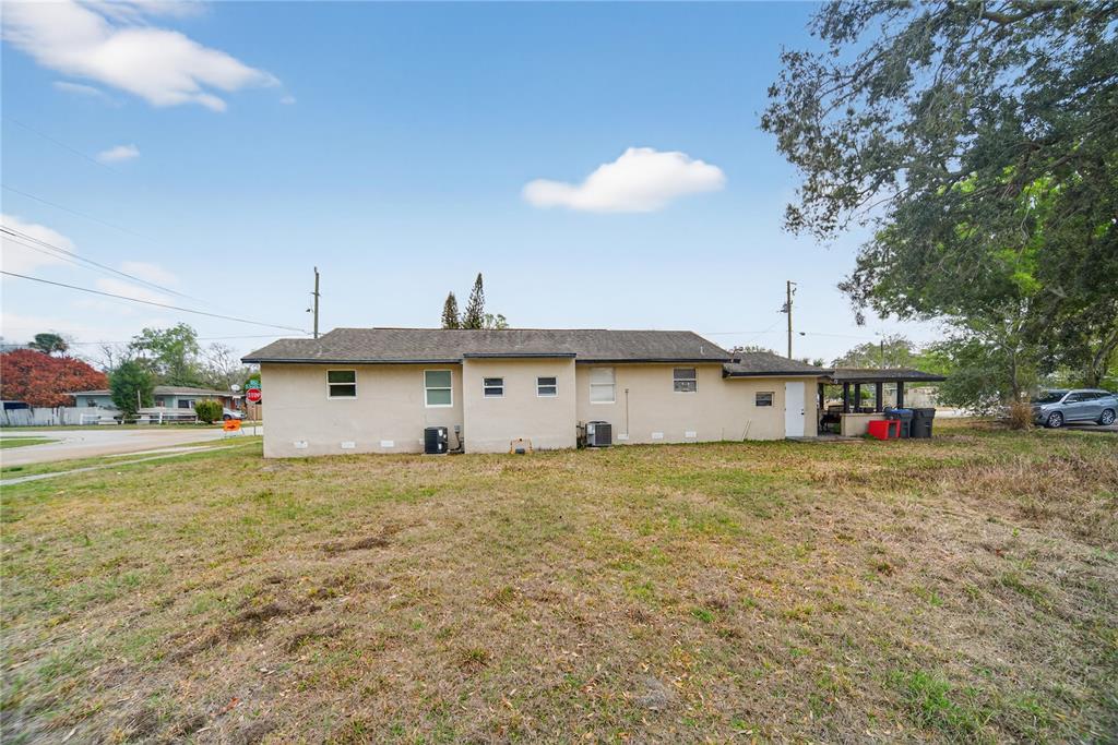 The exterior of a single-story beige house with a yard and a covered patio — 514 S GRANNIS AVENUE, TITUSVILLE, FL