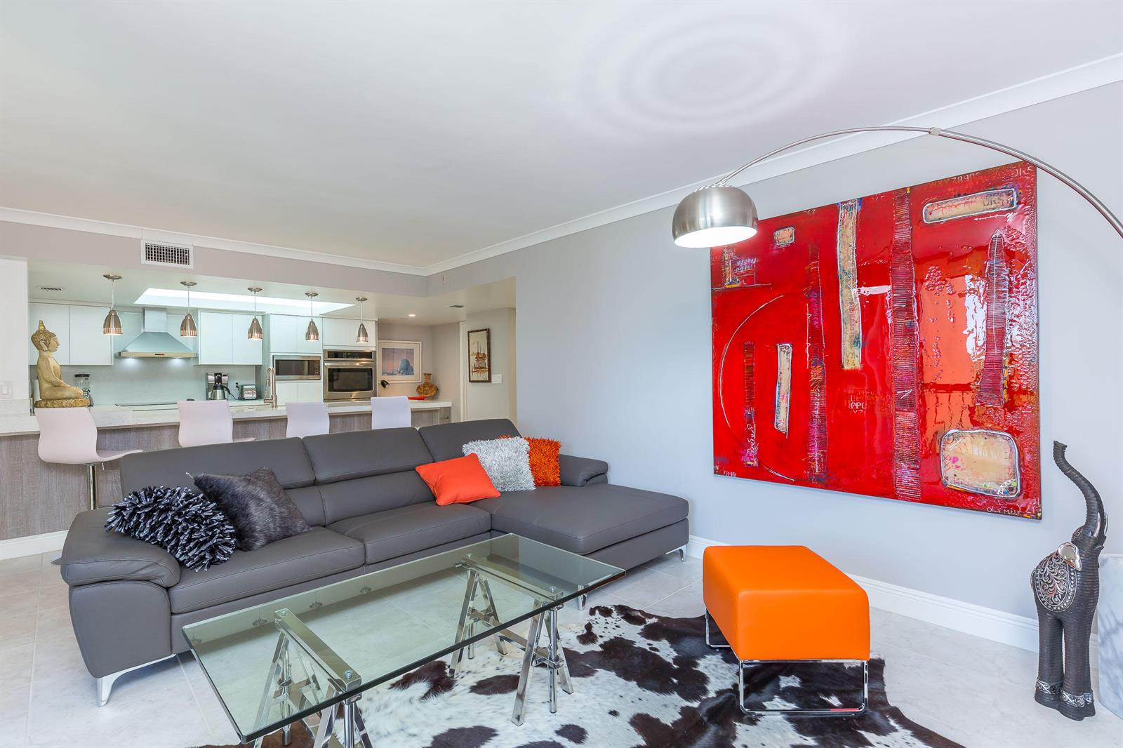 A living room features a grey sectional sofa, a glass coffee table, and large red artwork — 2455 Lindell Boulevard # 3304, Delray Beach FL 33444, DELRAY BEACH, FL
