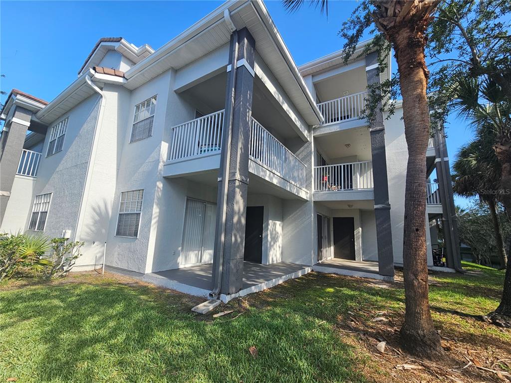 A multi-story apartment building exterior features white stucco walls, dark columns, and private balconies — 13838 FAIRWAY ISLAND DRIVE UNIT 1418, ORLANDO, FL