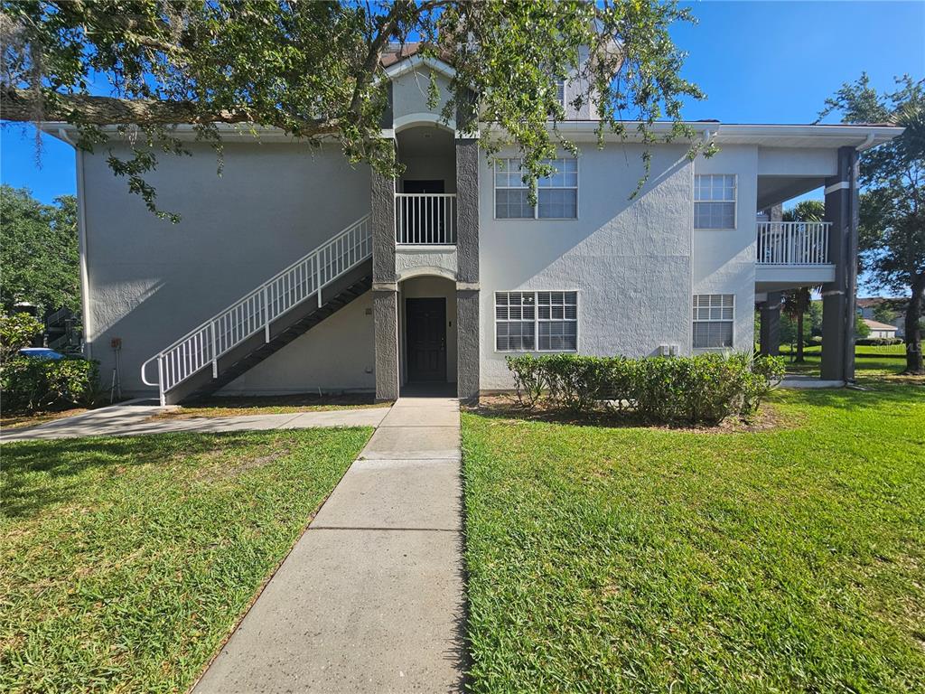 A two-story apartment building exterior features a concrete staircase, a balcony, and a front entrance — 13838 FAIRWAY ISLAND DRIVE UNIT 1418, ORLANDO, FL