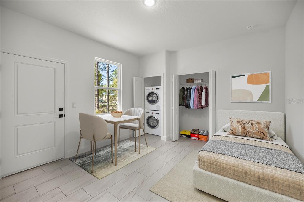 A bedroom features a bed, a small dining table, and a stacked washer and dryer — 10735 N MALVA WAY DRIVE, CITRUS SPRINGS, FL