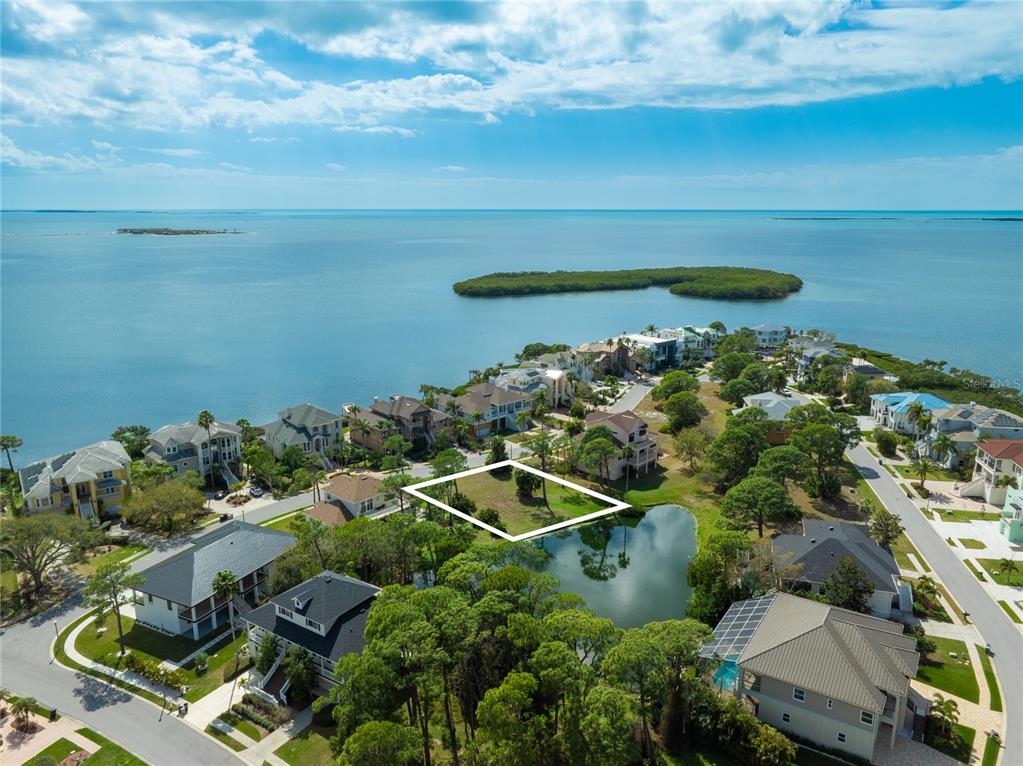 An aerial view shows a vacant residential lot outlined in white next to a small pond — HARBOUR WATCH CIRCLE, TARPON SPRINGS, FL
