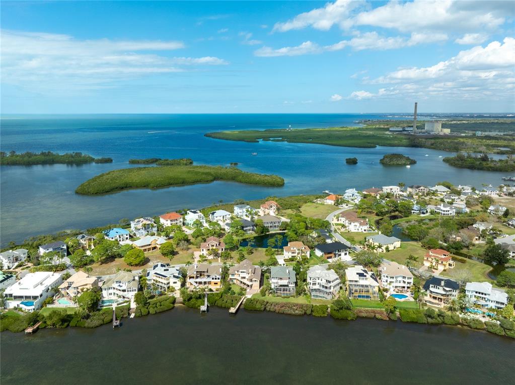 An aerial view shows waterfront homes along a coastal inlet with a power plant nearby — HARBOUR WATCH CIRCLE, TARPON SPRINGS, FL