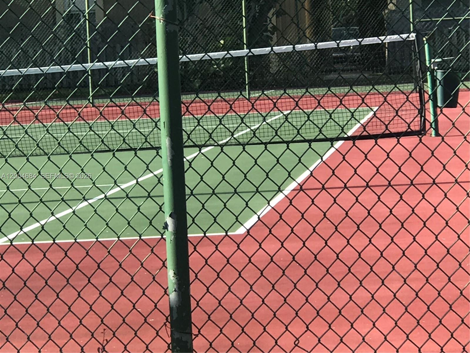 A chain-link fence surrounds a green and red tennis court — 5112 NW 79 AV # 201, Doral FL 33166, DORAL, FL