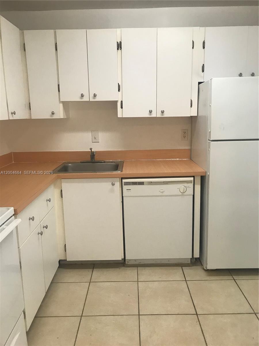 A kitchen features white cabinets, a light-colored countertop, a dishwasher, and a white refrigerator — 5112 NW 79 AV # 201, Doral FL 33166, DORAL, FL
