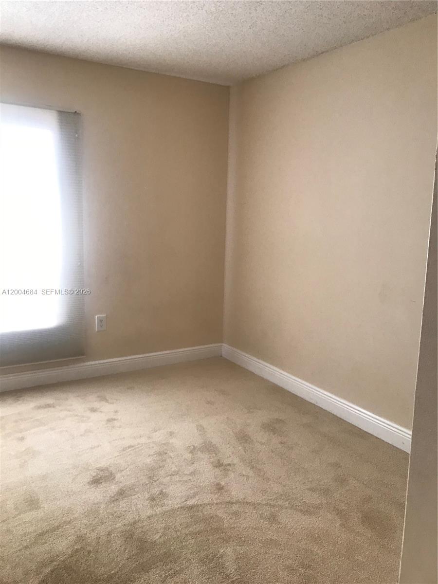 An empty bedroom features beige carpet, light-colored walls, and a window with a blind — 5112 NW 79 AV # 201, Doral FL 33166, DORAL, FL