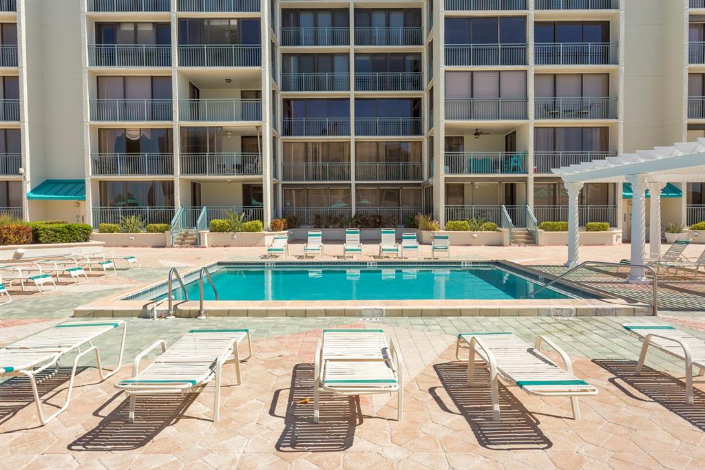 A swimming pool with lounge chairs on a paved deck in front of a large building — 1380 GULF BOULEVARD UNIT 206, CLEARWATER, FL