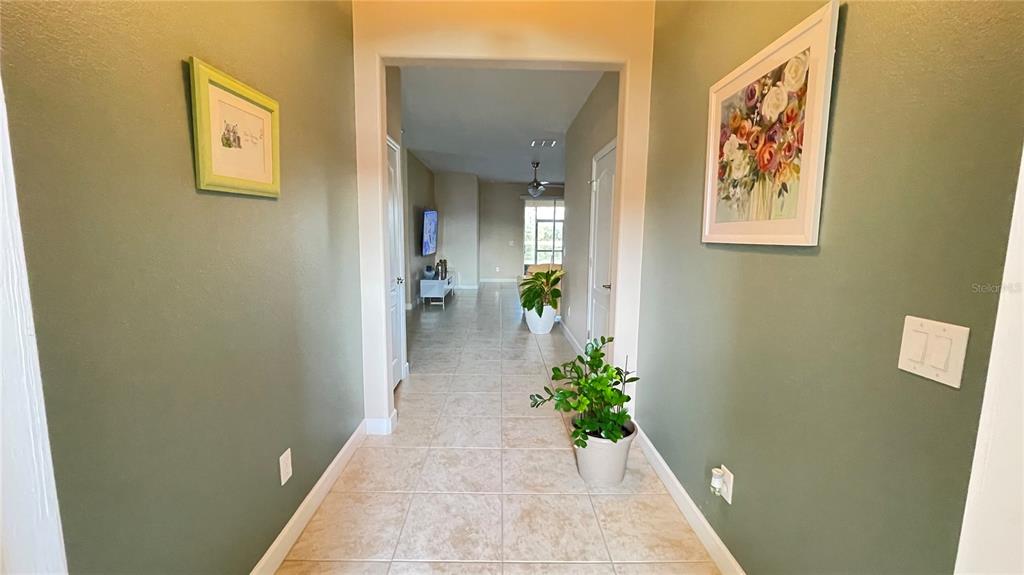 A tiled entryway leads into a living area with green walls and framed artwork — 14112 QUEENSIDE ST, ORLANDO, FL