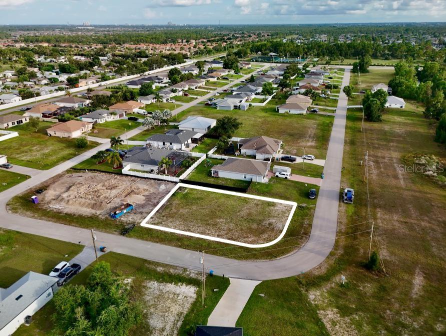 An aerial view shows a vacant residential lot outlined in white within a suburban neighborhood — 3829 NE 23RD AVENUE, CAPE CORAL, FL