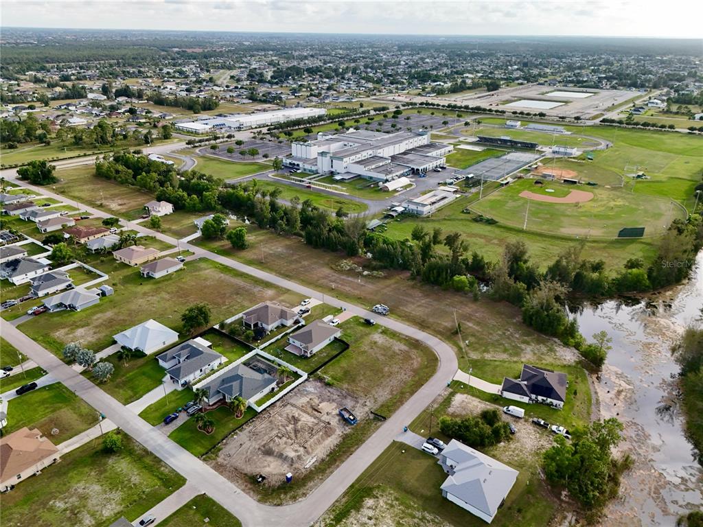 An aerial view shows a suburban neighborhood with houses, a school, and a baseball field — 3829 NE 23RD AVENUE, CAPE CORAL, FL