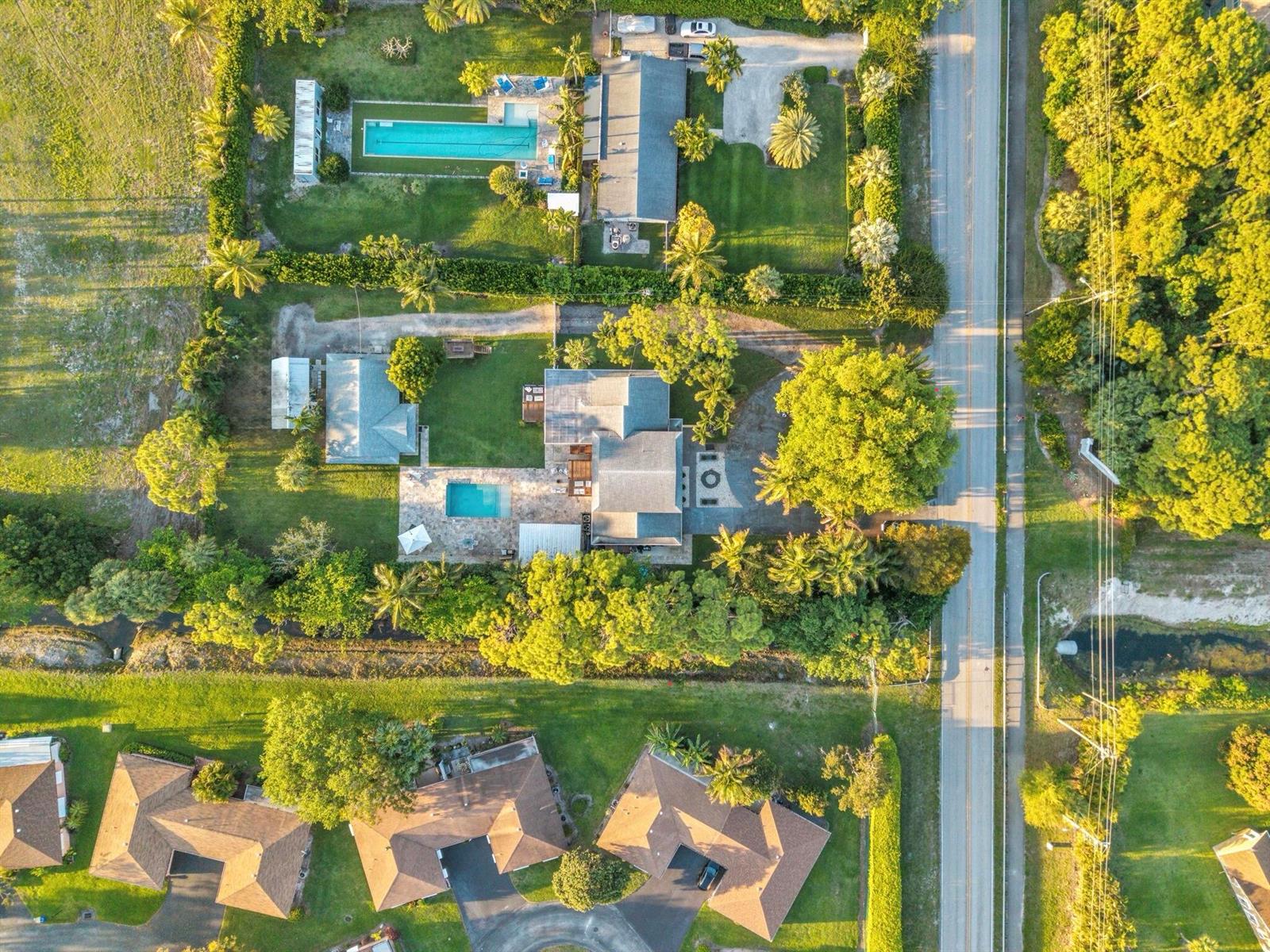 An aerial view shows two residential properties with swimming pools, lawns, and surrounding trees — 13487 Barwick Road # B, Delray Beach FL 33445, DELRAY BEACH, FL