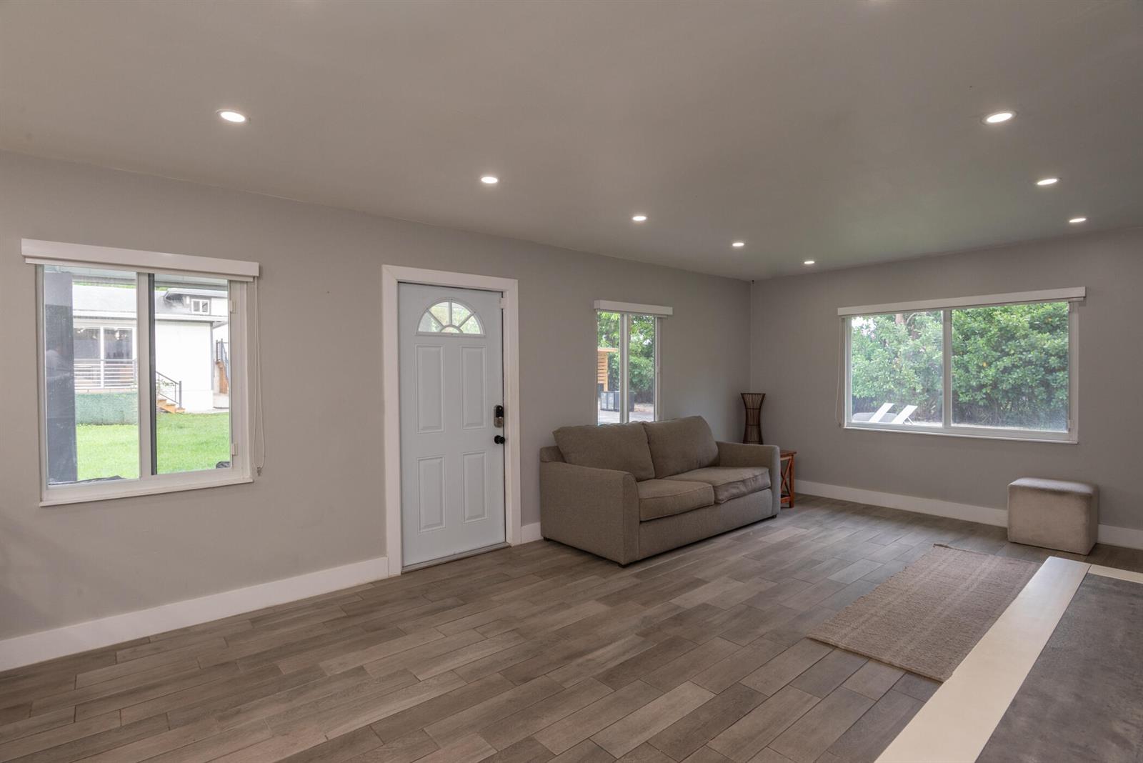 A living room features gray walls, wood-look tile flooring, recessed lighting, and a light-colored sofa — 13487 Barwick Road # B, Delray Beach FL 33445, DELRAY BEACH, FL