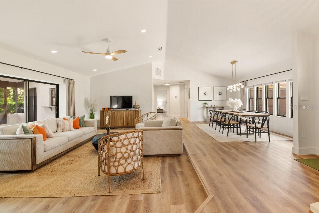 An open-concept living and dining area features vaulted ceilings, light wood flooring, and neutral furniture — 31 PENNSYLVANIA LANE, PALM COAST, FL