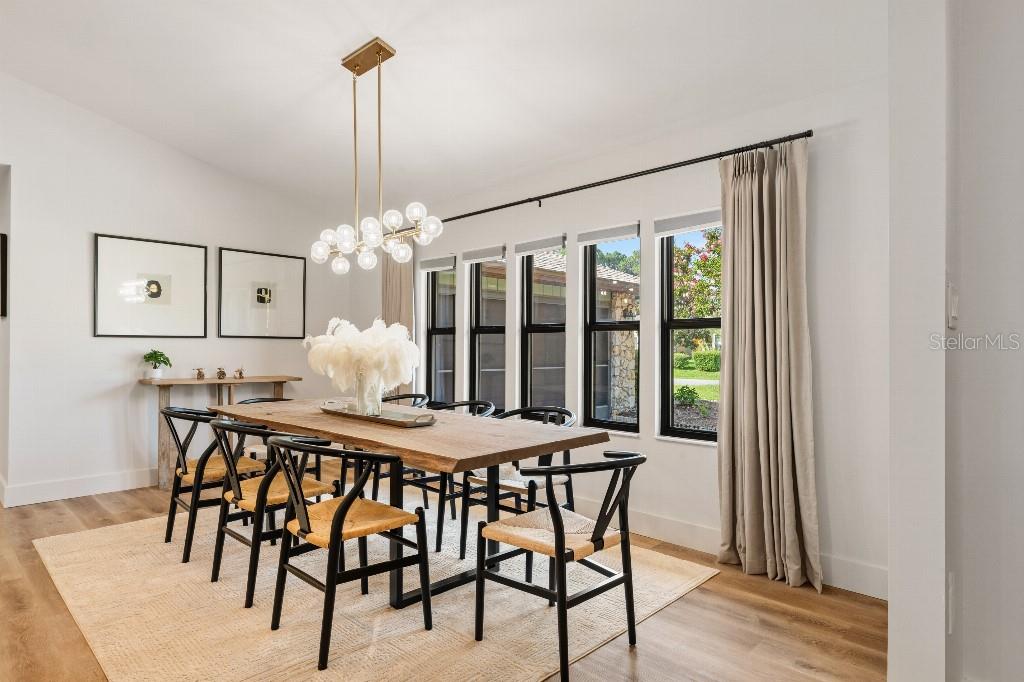 A dining room features a wooden table, black chairs, a modern chandelier, and large windows — 31 PENNSYLVANIA LANE, PALM COAST, FL