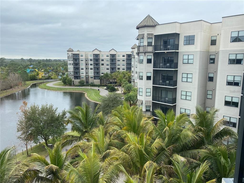 An exterior view of a multi-story apartment building overlooking a pond and palm trees — 14501 GROVE RESORT AVENUE UNIT 1612, WINTER GARDEN, FL