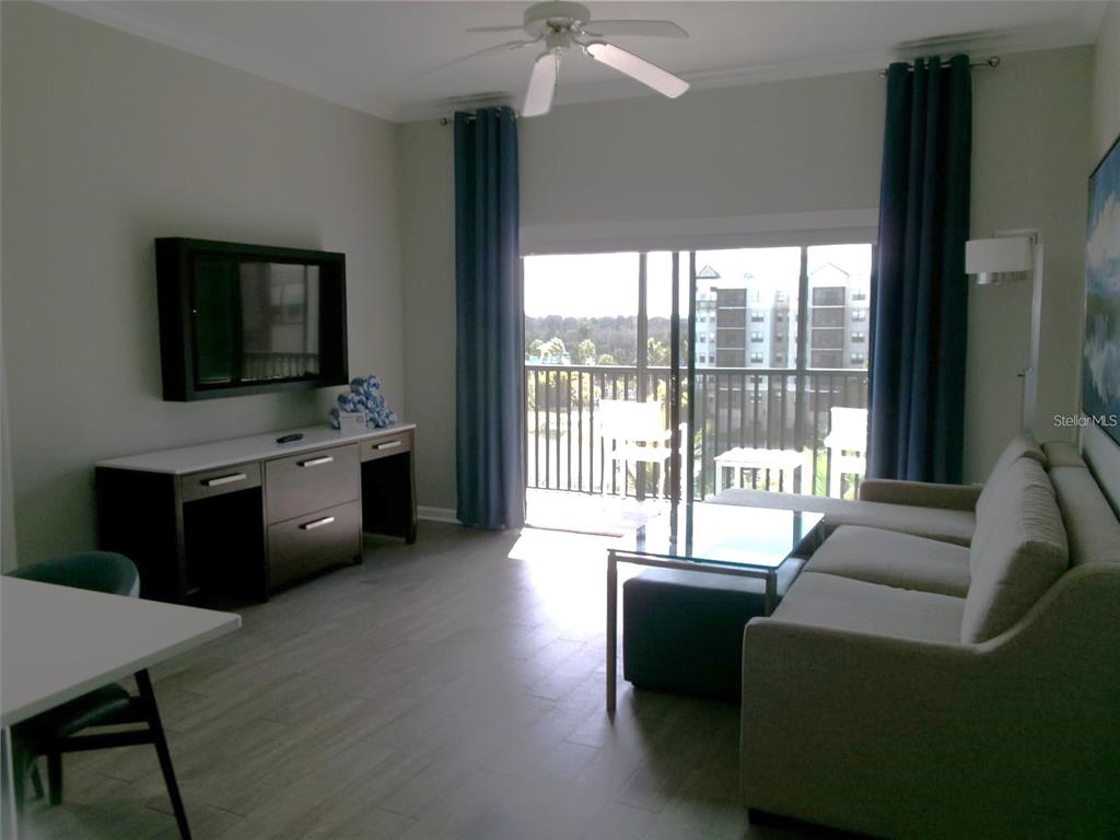 A living room features a sofa, media console, ceiling fan, and sliding doors to a balcony — 14501 GROVE RESORT AVENUE UNIT 1612, WINTER GARDEN, FL