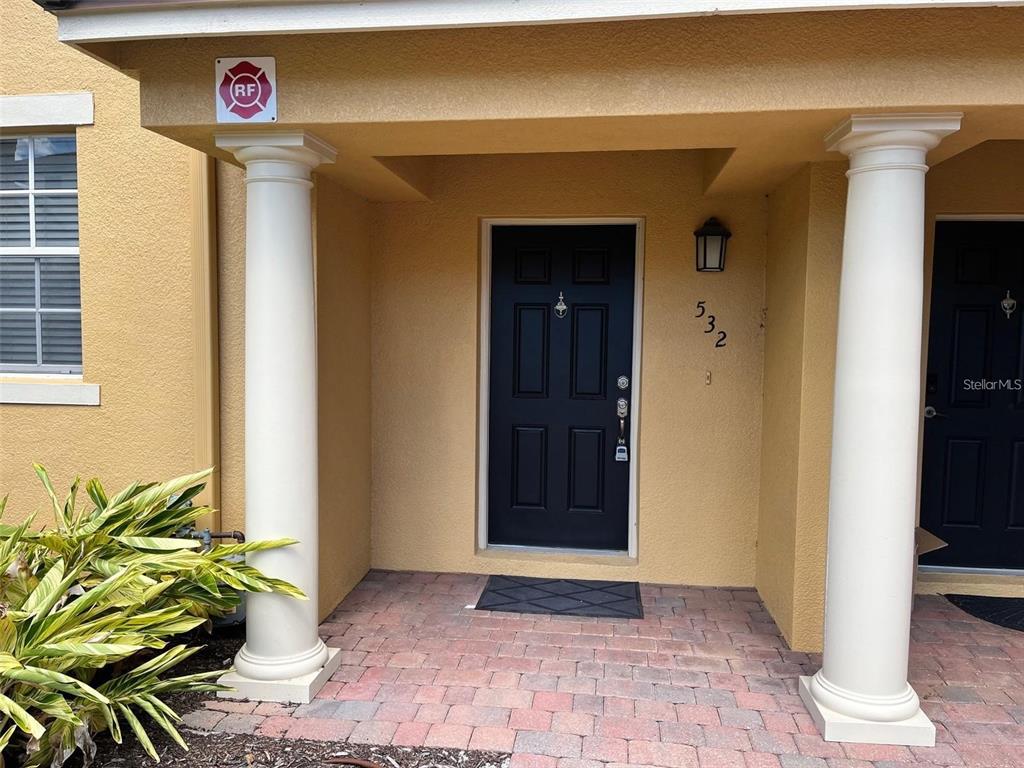 A front entrance with a black door, two white columns, and a brick porch — 532 JASMINE WAY, CLEARWATER, FL