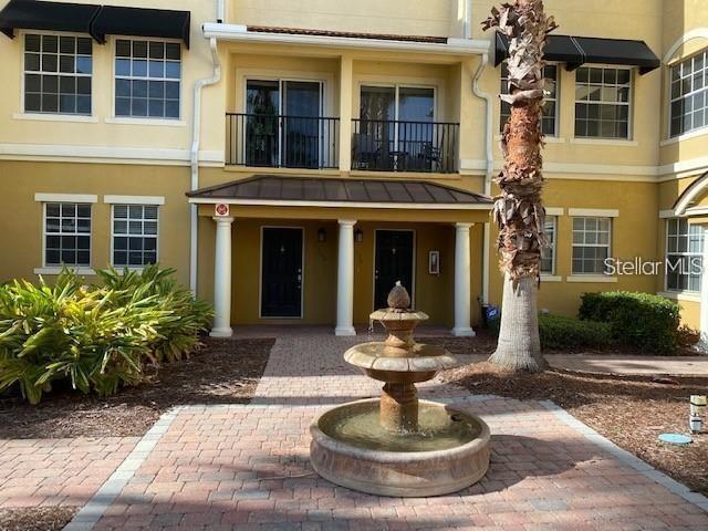 A stone fountain sits on a brick patio in front of a multi-story apartment building — 532 JASMINE WAY, CLEARWATER, FL