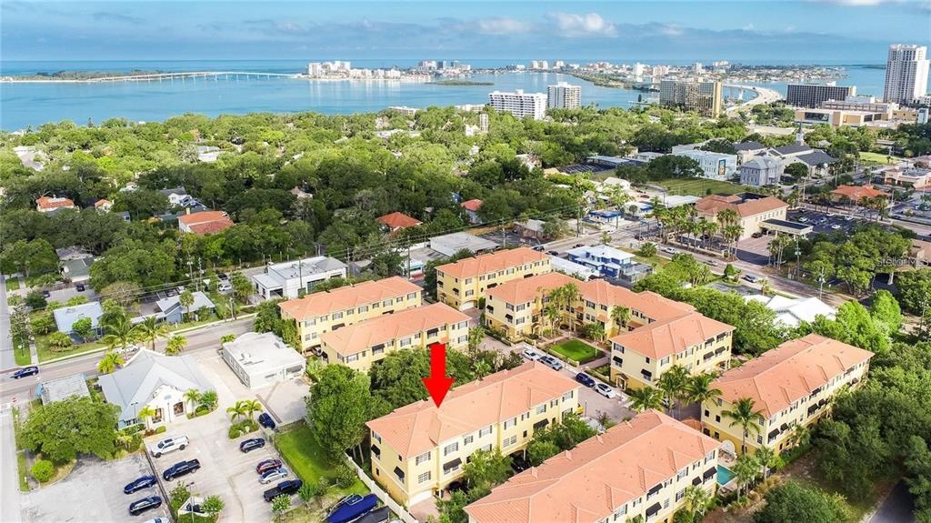 An aerial view shows a multi-story yellow residential complex with a red arrow pointing down — 532 JASMINE WAY, CLEARWATER, FL
