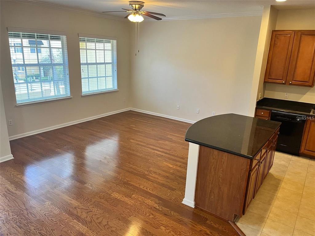 An open-concept dining area features hardwood floors, a ceiling fan, and an adjacent kitchen island — 532 JASMINE WAY, CLEARWATER, FL