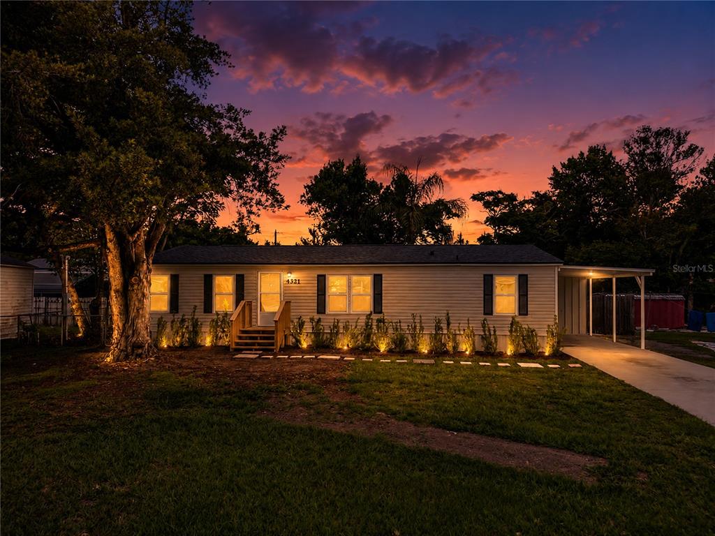 A single-story house with light siding and a carport at dusk under a sunset sky — 4321 SPARTAN DRIVE, ORLANDO, FL