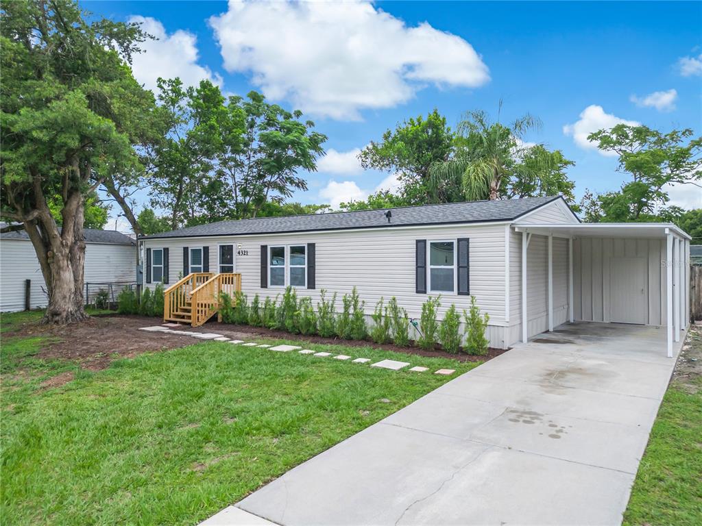 A single-story manufactured home with light siding, a front porch, and an attached carport — 4321 SPARTAN DRIVE, ORLANDO, FL