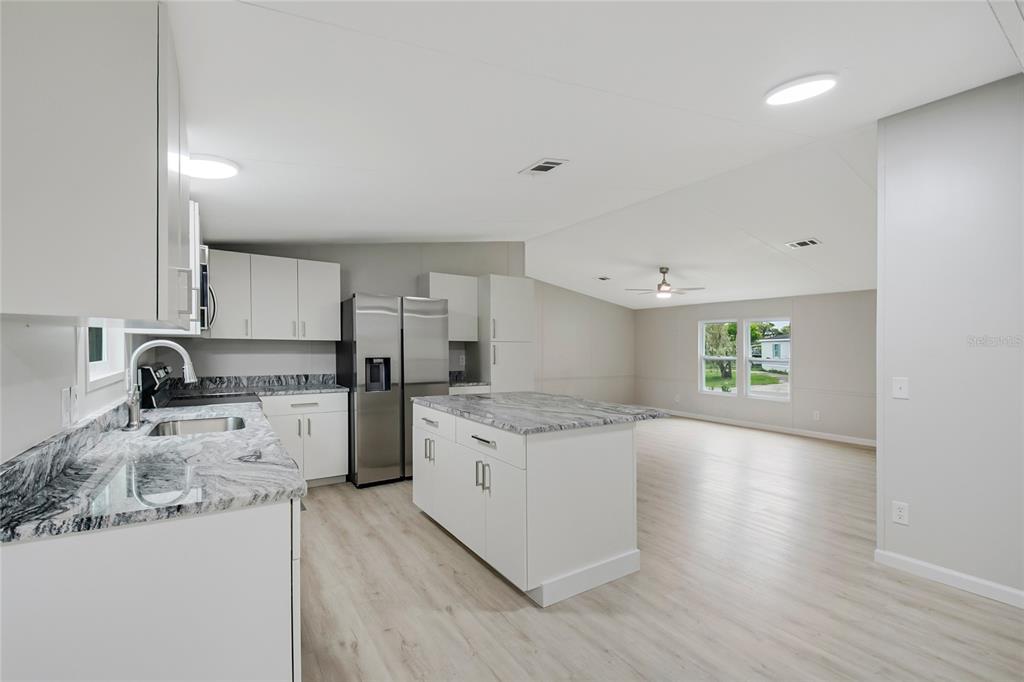 A modern kitchen with white cabinets, granite countertops, and an island opens to a living area — 4321 SPARTAN DRIVE, ORLANDO, FL