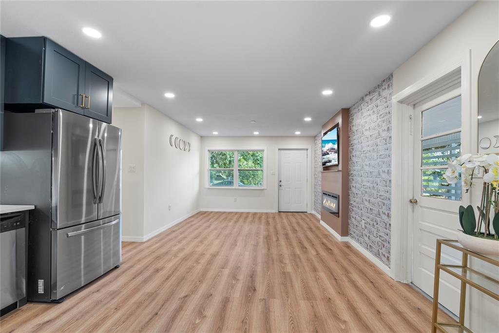 A kitchen and living area feature wood-look flooring, recessed lighting, and a brick-patterned accent wall — 607 WALNUT DRIVE, FORT MEADE, FL