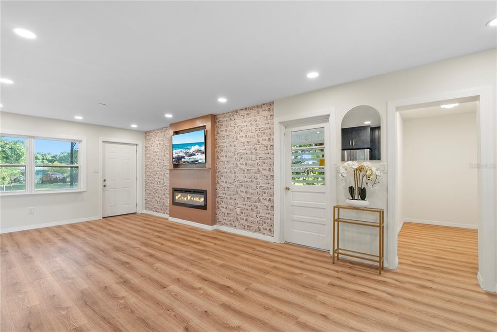 A living room with light wood flooring, a brick accent wall, and a built-in fireplace — 607 WALNUT DRIVE, FORT MEADE, FL