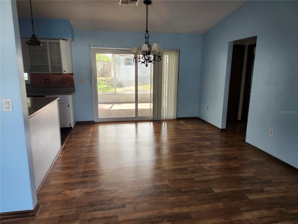 A dining area features light blue walls, wood-look flooring, a chandelier, and sliding glass doors — 10115 HAYWARD ROAD, SPRING HILL, FL