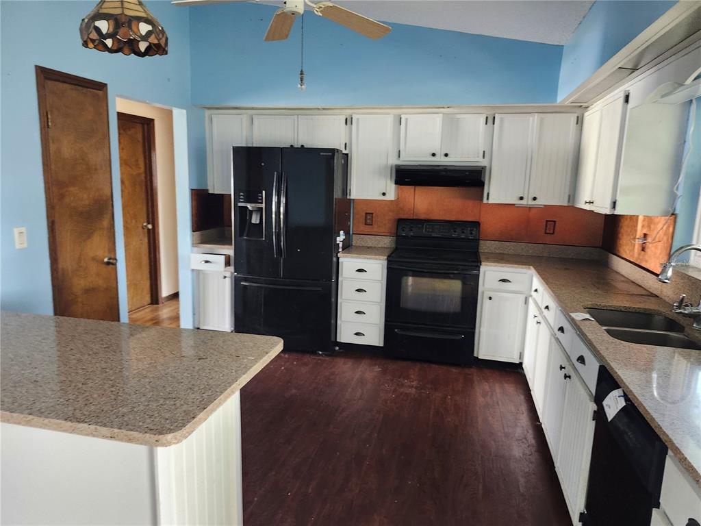 A kitchen features white cabinets, black appliances, granite countertops, and dark wood-look flooring — 10115 HAYWARD ROAD, SPRING HILL, FL