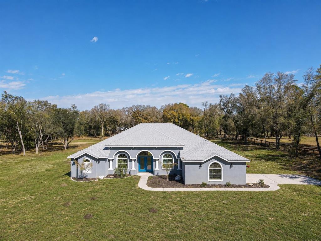 A gray, single-story house with a hip roof sits on a large, grassy lot — 10688 SW 129TH TERRACE ROAD, DUNNELLON, FL