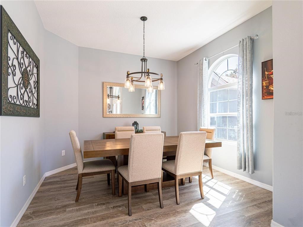 A dining room features a wooden table, six upholstered chairs, a chandelier, and a mirror — 10688 SW 129TH TERRACE ROAD, DUNNELLON, FL