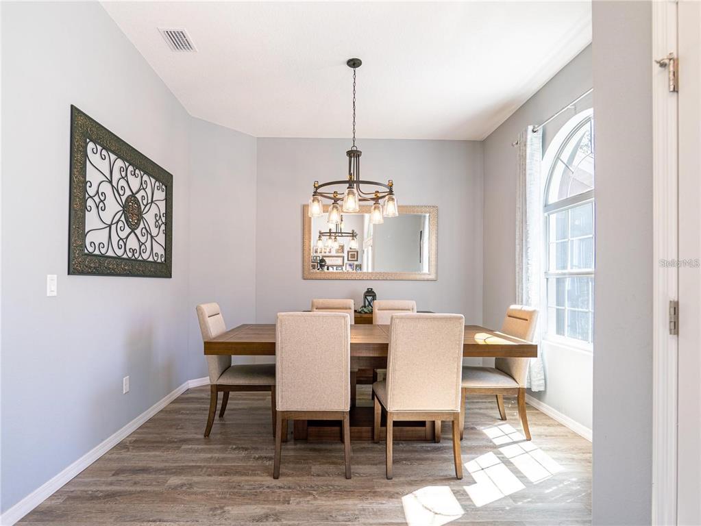 A dining room features a wooden table, six upholstered chairs, a chandelier, and a mirror — 10688 SW 129TH TERRACE ROAD, DUNNELLON, FL
