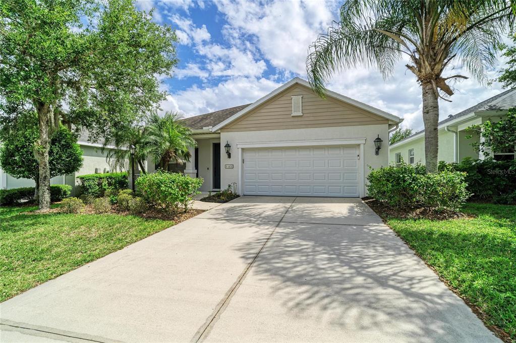A single-story house with a beige stucco exterior, a two-car garage, and a concrete driveway — 4650 WOODBROOK DRIVE, SARASOTA, FL