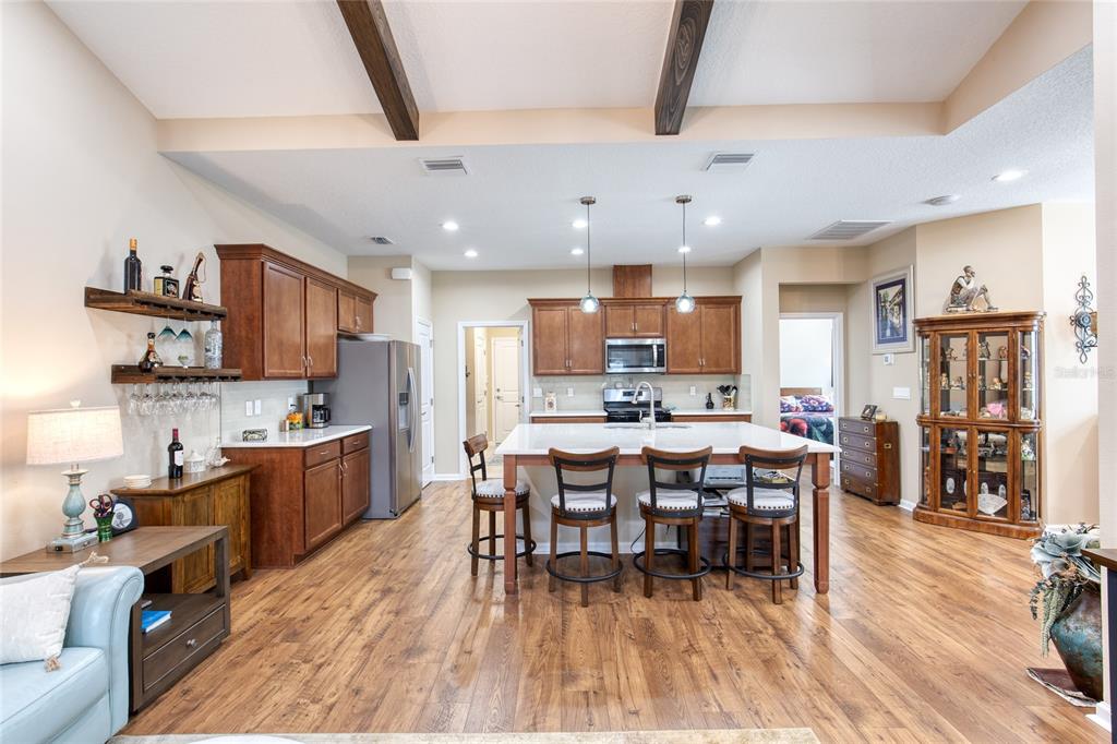 A kitchen with wood cabinets, a central island with bar seating, and wood-look flooring — 224 GYPSY PALACE LANE, DAYTONA BEACH, FL