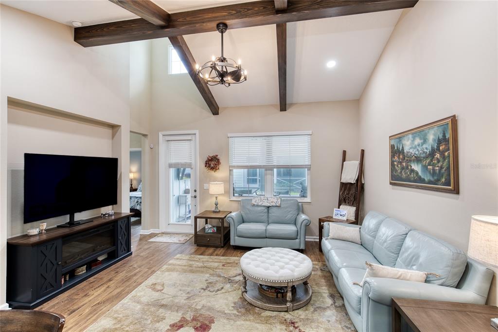 A living room features vaulted ceilings with exposed wooden beams, light blue sofas, and flooring — 224 GYPSY PALACE LANE, DAYTONA BEACH, FL