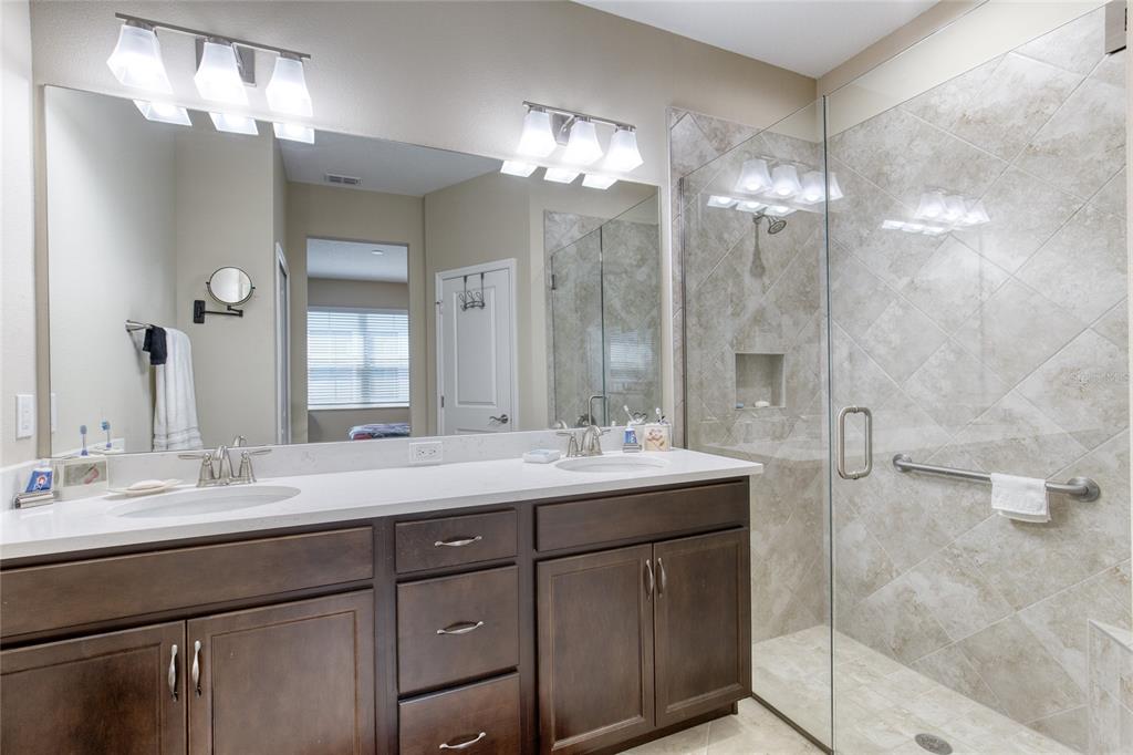 A bathroom features a double vanity with dark wood cabinets and a glass-enclosed tiled shower — 224 GYPSY PALACE LANE, DAYTONA BEACH, FL